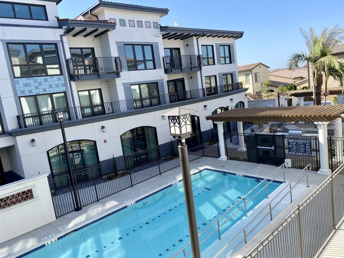 A modern apartment complex with a swimming pool and balconies.