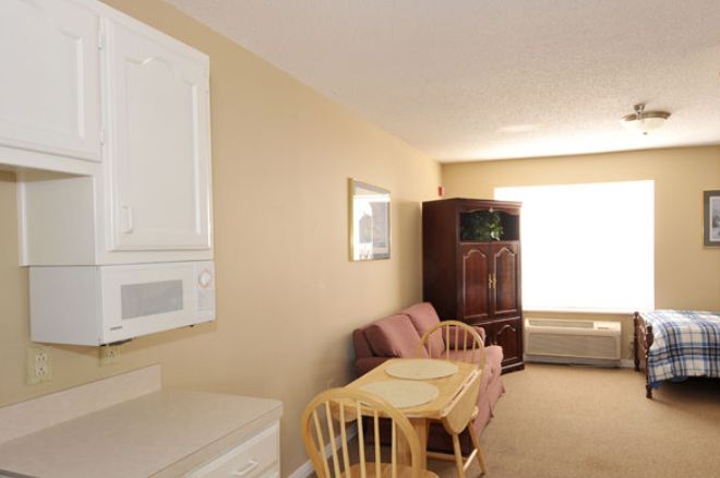 A cozy living area featuring a sofa, wooden table with chairs, and a cabinet near a window.