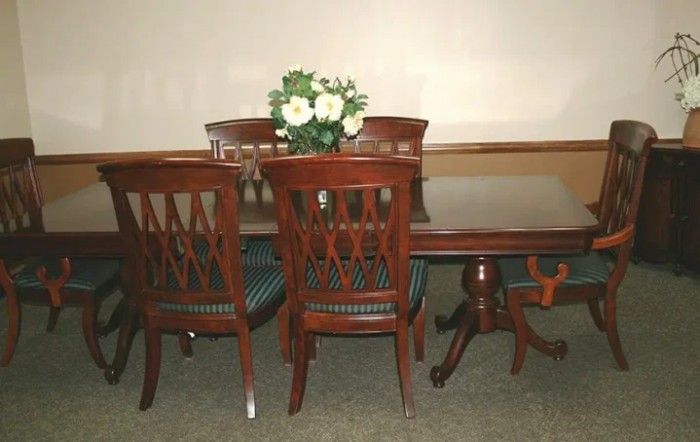 A wooden dining table set with four chairs and a centerpiece of white flowers.
