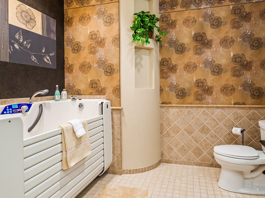 A cozy bathroom featuring a walk-in bathtub, decorative wallpaper, and tile flooring.