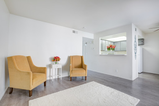 A modern and minimalist living room setup featuring two yellow chairs and a small side table with flowers.