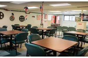 An empty cafeteria with rows of tables and chairs, decorated with hanging ornaments.