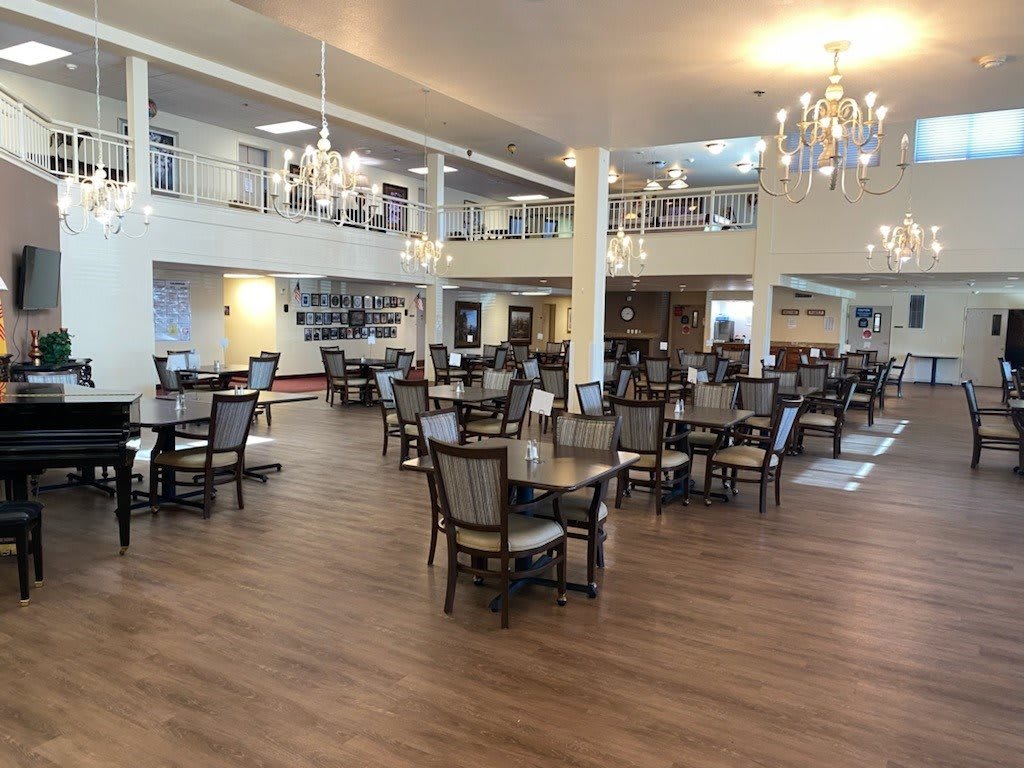 A spacious and elegantly decorated dining area with multiple tables, chairs, and chandeliers.