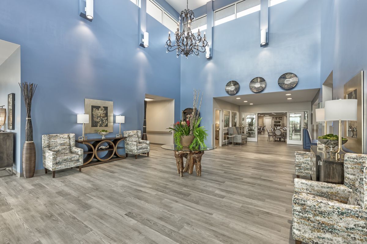 A spacious and elegantly decorated lobby featuring a chandelier, blue walls, and modern furnishings.