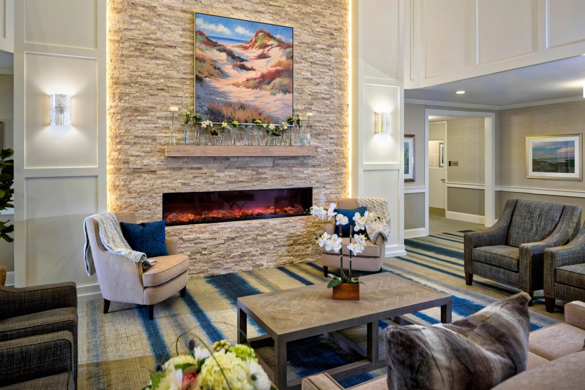 A cozy living room with a stone fireplace, modern decor, and comfortable seating.