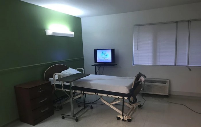 An empty hospital room with a bed and a television.