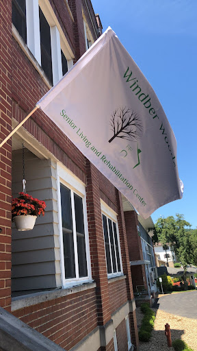 A flag advertising a business, accompanied by a flower pot, against a brick building backdrop.