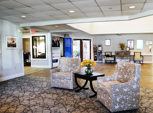 A cozy lobby area featuring patterned chairs and a small table with flowers.