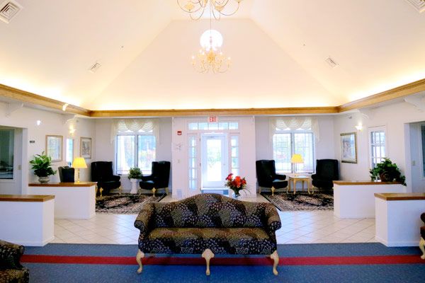 A spacious and elegantly decorated lobby area with a central sofa, complemented by ambient lighting from chandeliers and large windows.