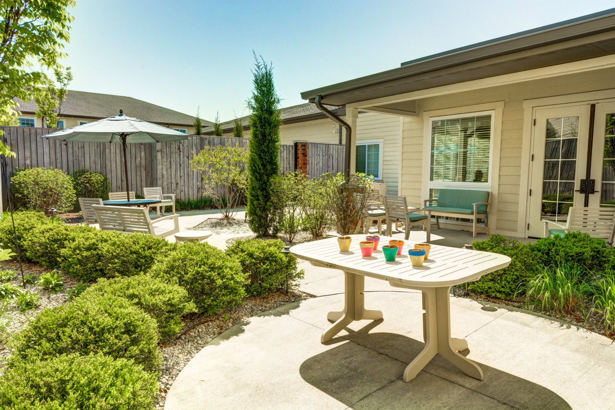 A sunny patio with a table, chairs, and well-maintained garden.