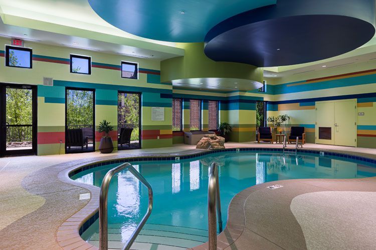 A vibrant indoor swimming pool with colorful walls and a modern ceiling design.