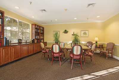 A cozy conference room with a large table, chairs, and bookshelves.