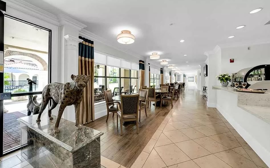 A spacious and elegantly decorated dining area with tables and chairs arranged alongside large windows.