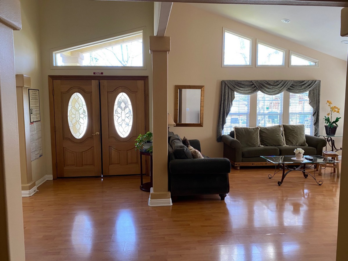 A well-lit living room with hardwood floors, sofas, and large windows.