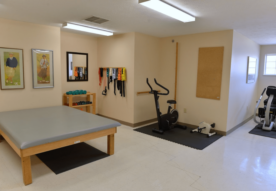 A physical therapy room featuring exercise equipment, including an exercise bike and resistance bands.