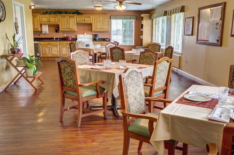 An inviting dining room with neatly arranged tables and chairs, featuring a view into a kitchen area.
