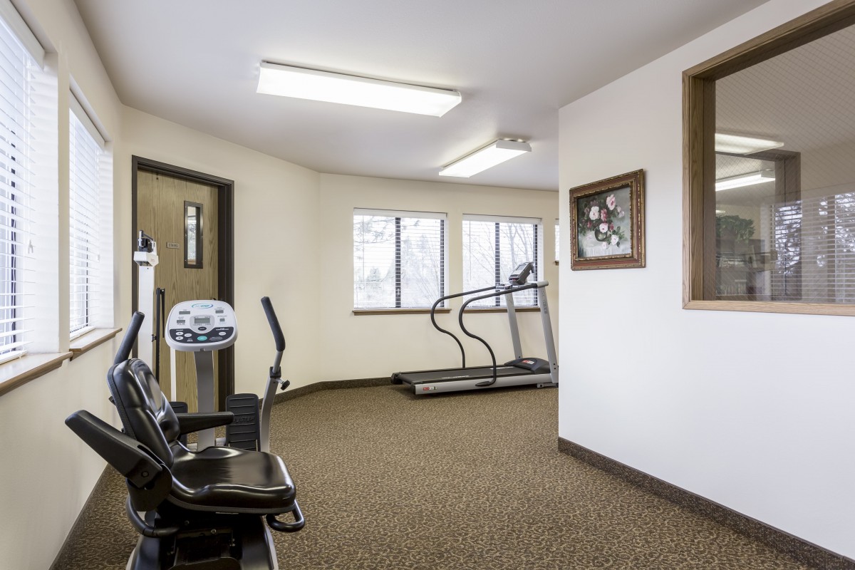 A small gym with exercise equipment including a treadmill and elliptical machine.