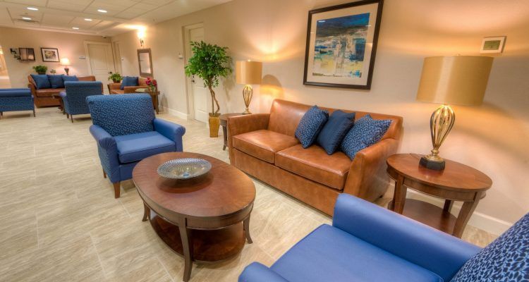 A cozy living room with a brown sofa, blue chairs, and a wooden coffee table.