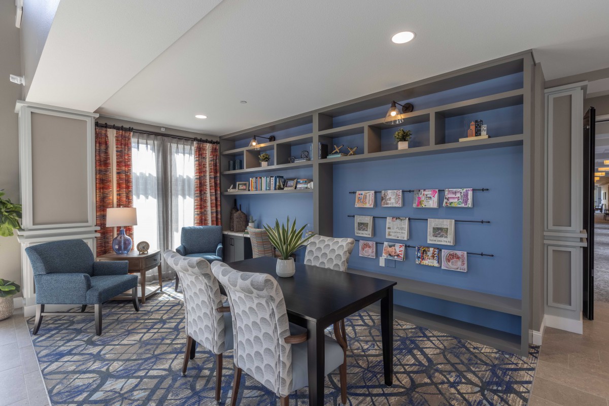 A cozy living room with blue walls, decorated shelves, and comfortable seating.