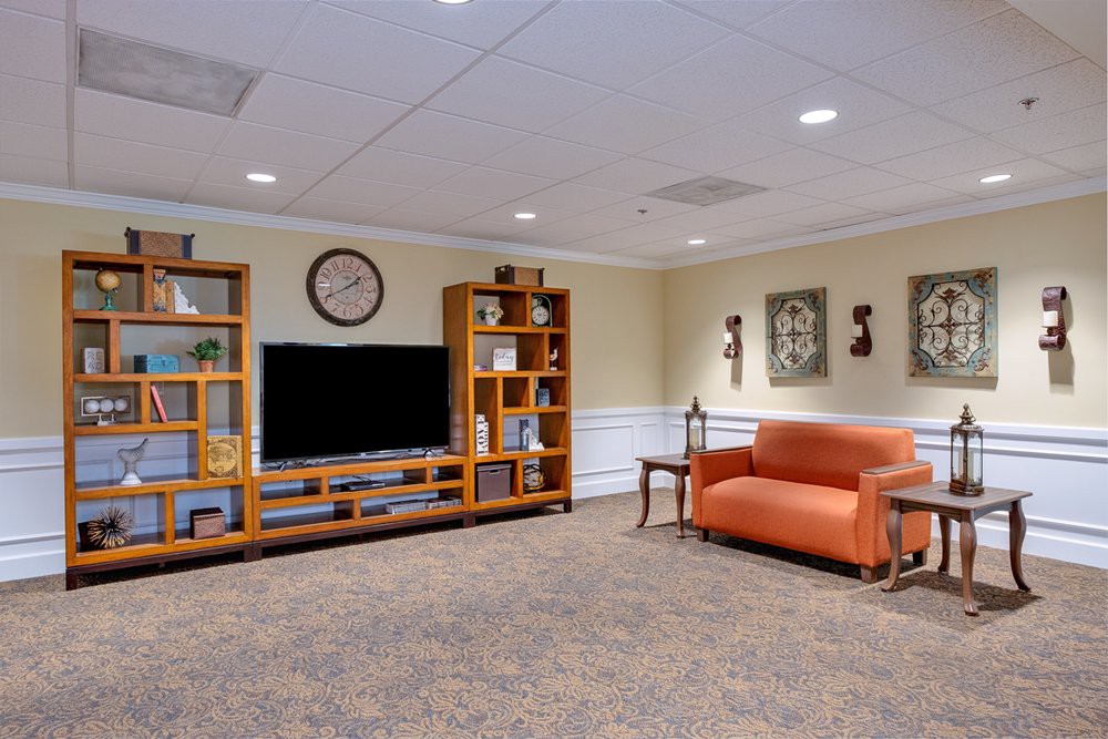 A cozy living room with a television, bookshelves, and comfortable seating.