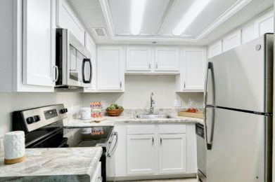 A modern kitchen with white cabinets and stainless steel appliances.