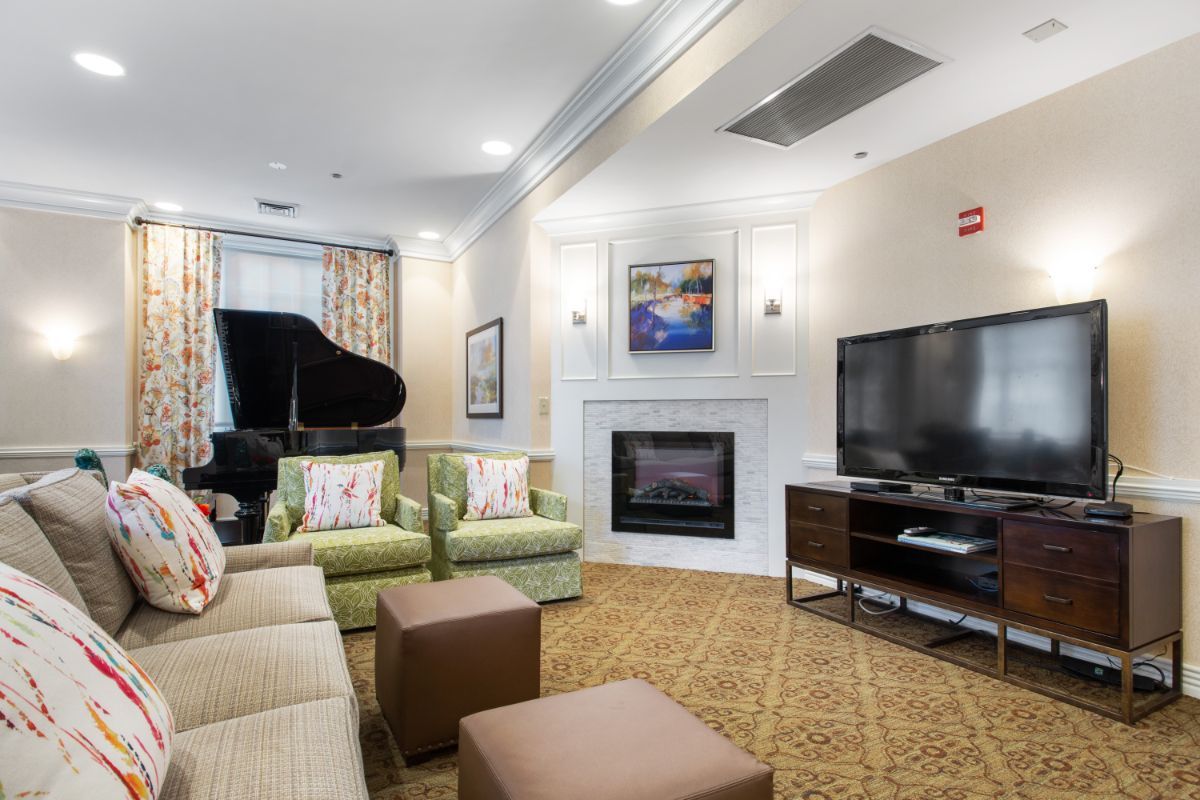 A modern living room with a fireplace, television, and grand piano.