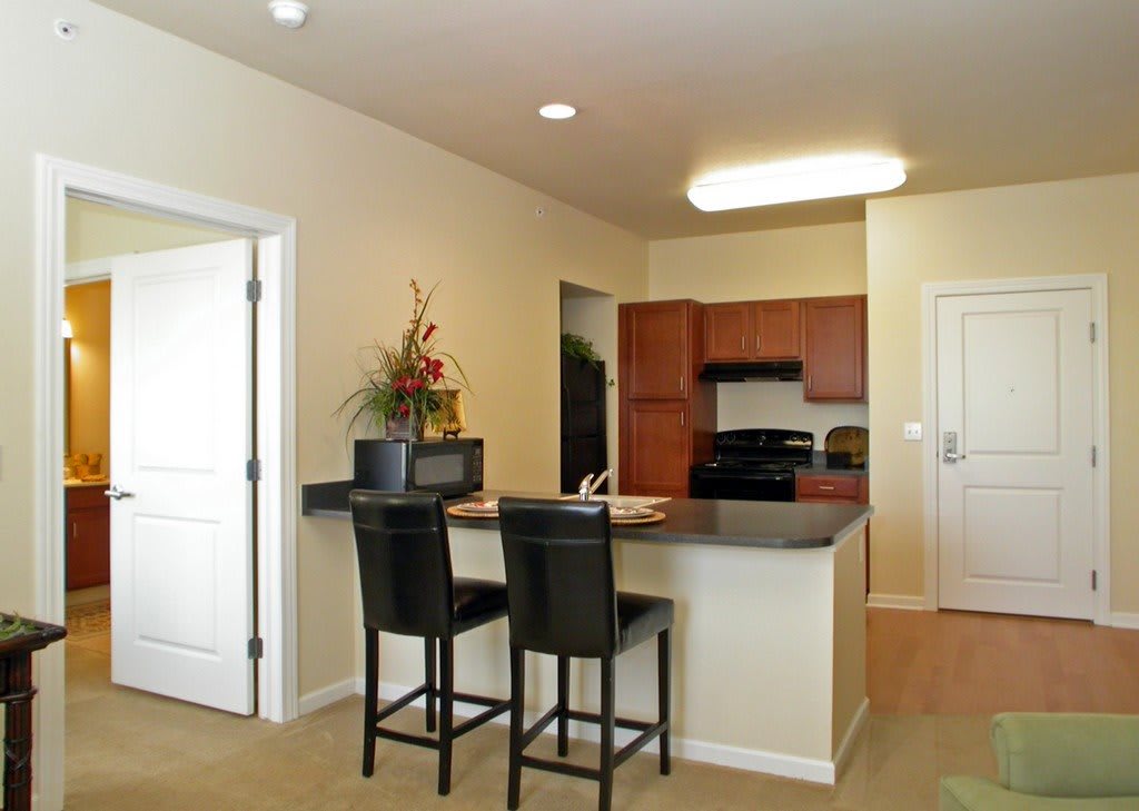 A modern apartment kitchen with a counter and two stools, featuring minimalist design elements.