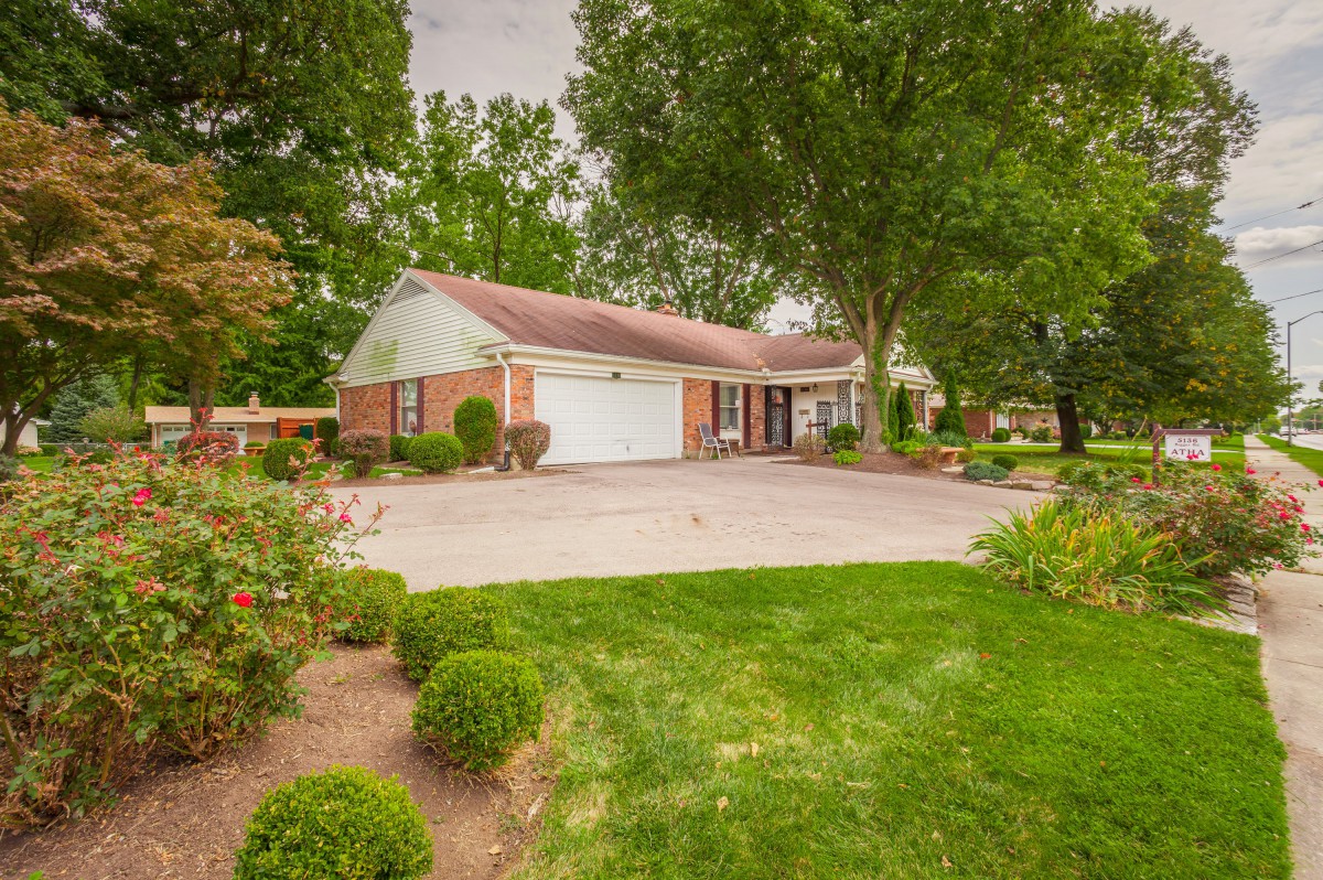 A suburban house with a garage and well-maintained lawn surrounded by trees.