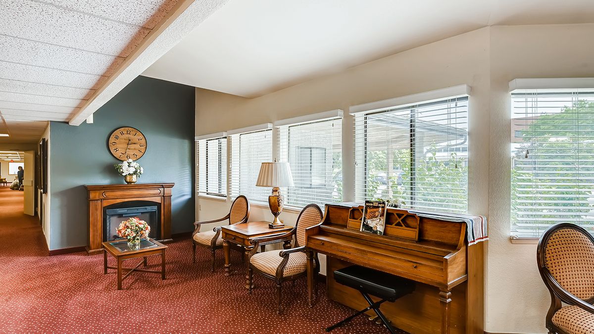 A cozy living room with a piano and elegant seating by large windows.