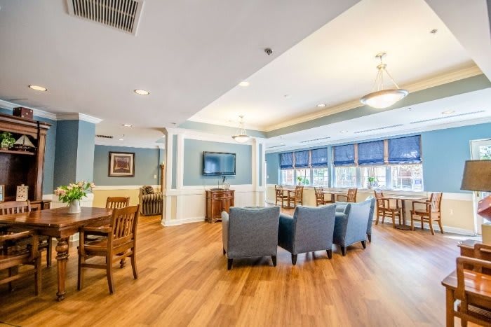 A modern lounge area with comfortable seating, wooden flooring, and bright natural light from the large windows.