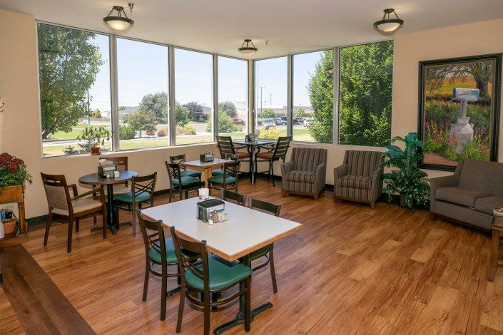 A cozy dining area with tables and chairs, featuring large windows overlooking the outdoors.