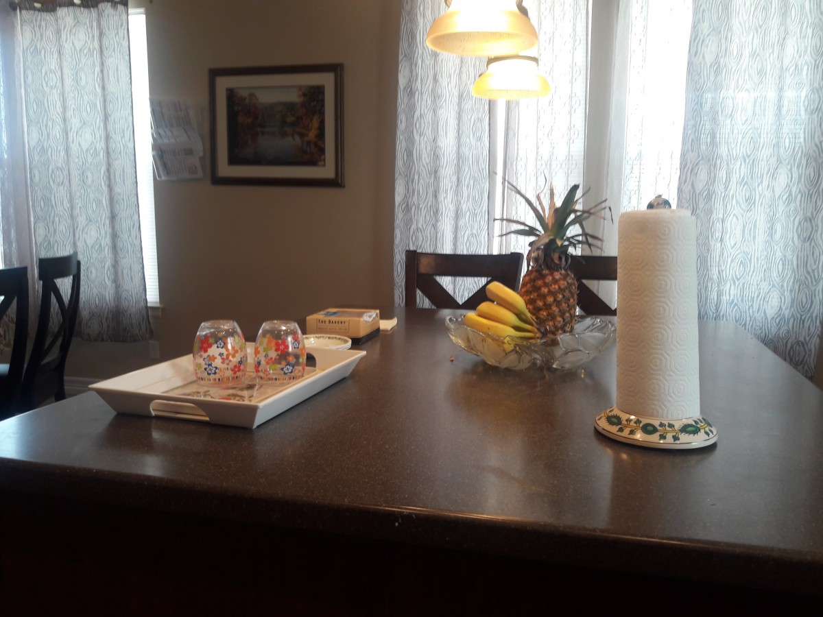 A kitchen island with a fruit bowl and glasses on a tray.