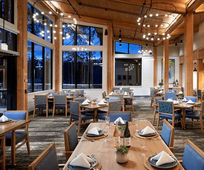 An elegant restaurant dining room with neatly set tables and large windows.