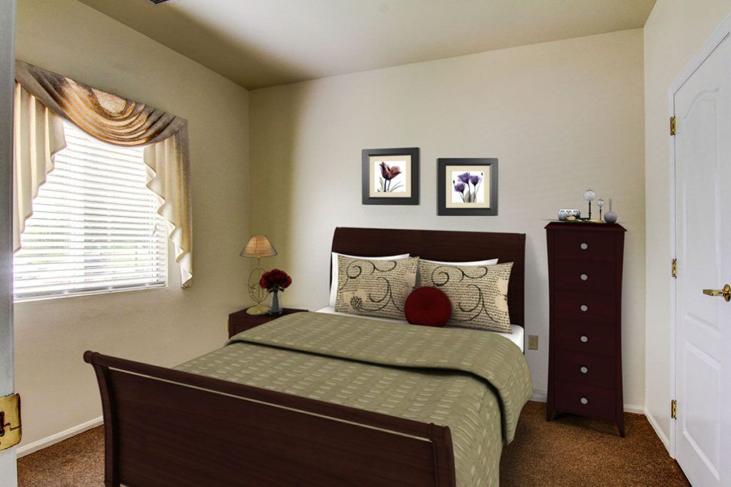 A cozy bedroom with a neatly made bed, decorated with floral pillows and artwork on the walls.