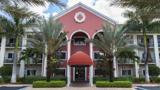 A vibrant commercial building with a red facade and palm trees framing the entrance.