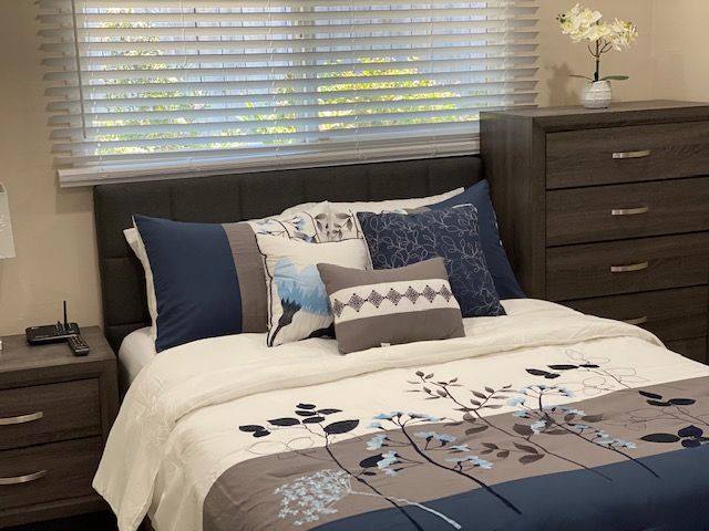 A neatly made bed with decorative pillows and a floral patterned blanket in a well-decorated bedroom.