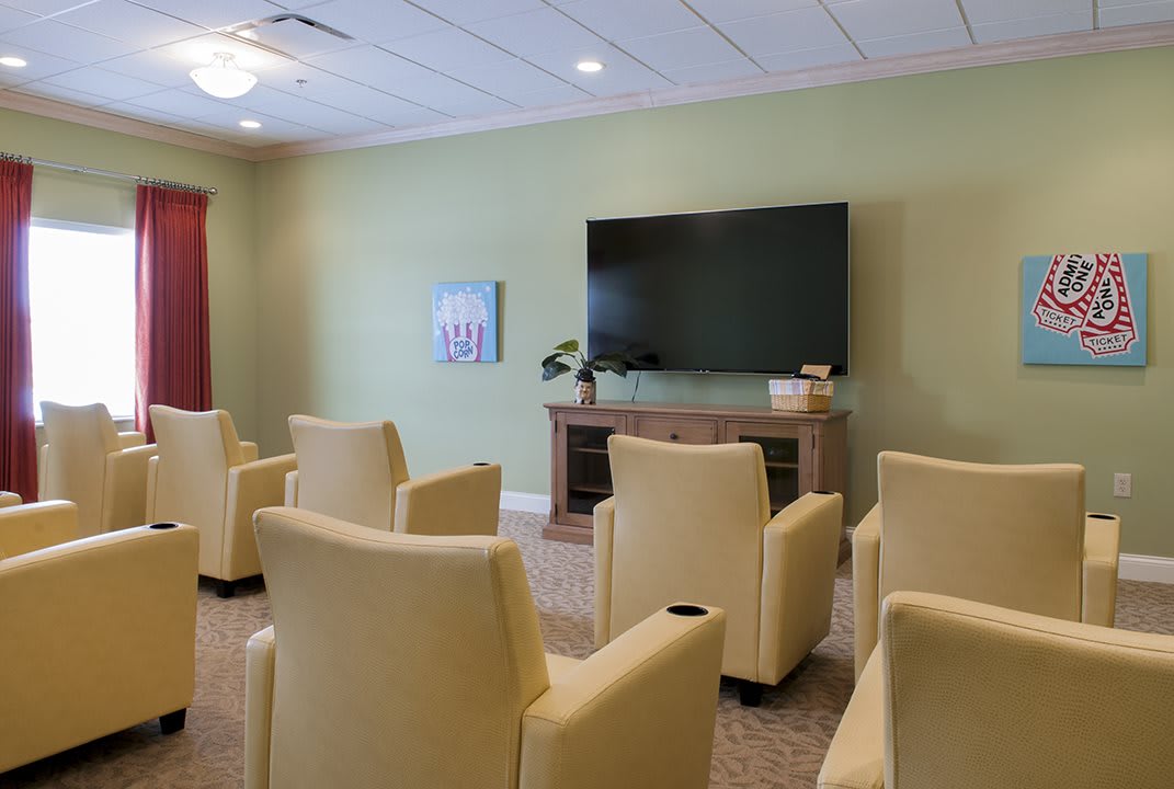 A seating area with multiple chairs facing a large television.
