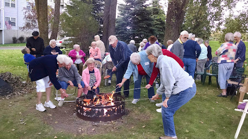 A lively community gathering around a campfire, where seniors share stories and enjoy each other's company.