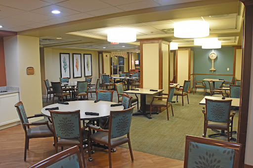A spacious dining area featuring neatly arranged tables and chairs, illuminated by soft lighting.