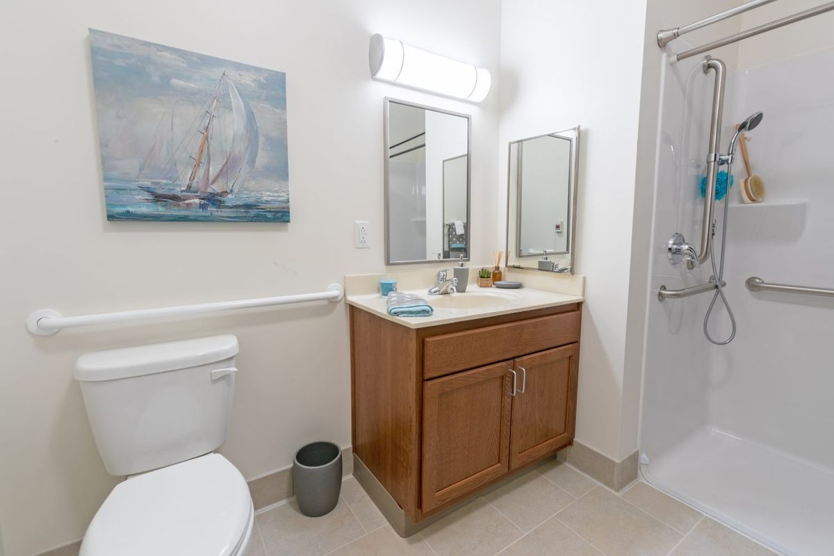 A modern bathroom with a wooden cabinet, mirrors, and light fixtures above the sink.
