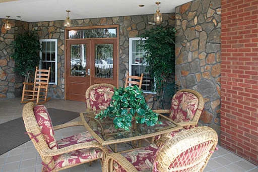 A cozy porch area featuring comfortable seating and a decorative glass table, surrounded by a stone wall.