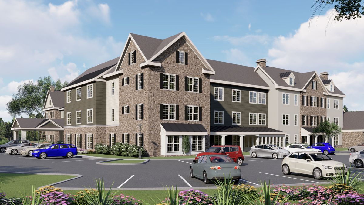 A modern residential building with a stone facade and a parking lot in front.