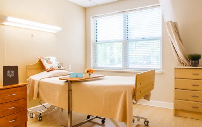 A clean and organized hospital room with a single patient bed and large windows.
