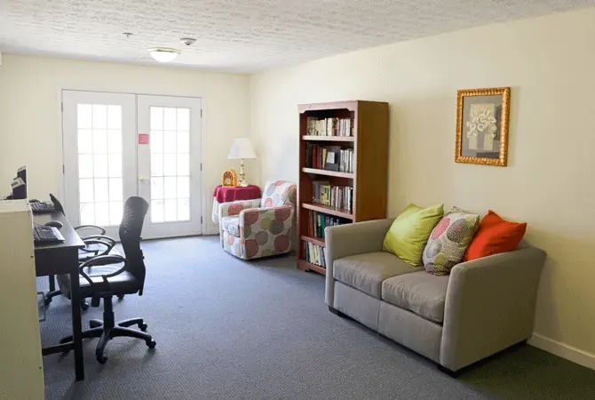 A cozy living room with a sofa, bookshelf, and desk chair.