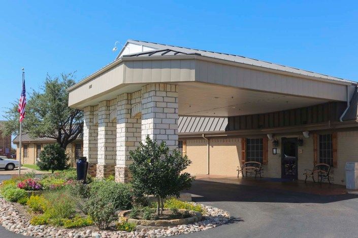 A building with a covered entrance and surrounding landscape.