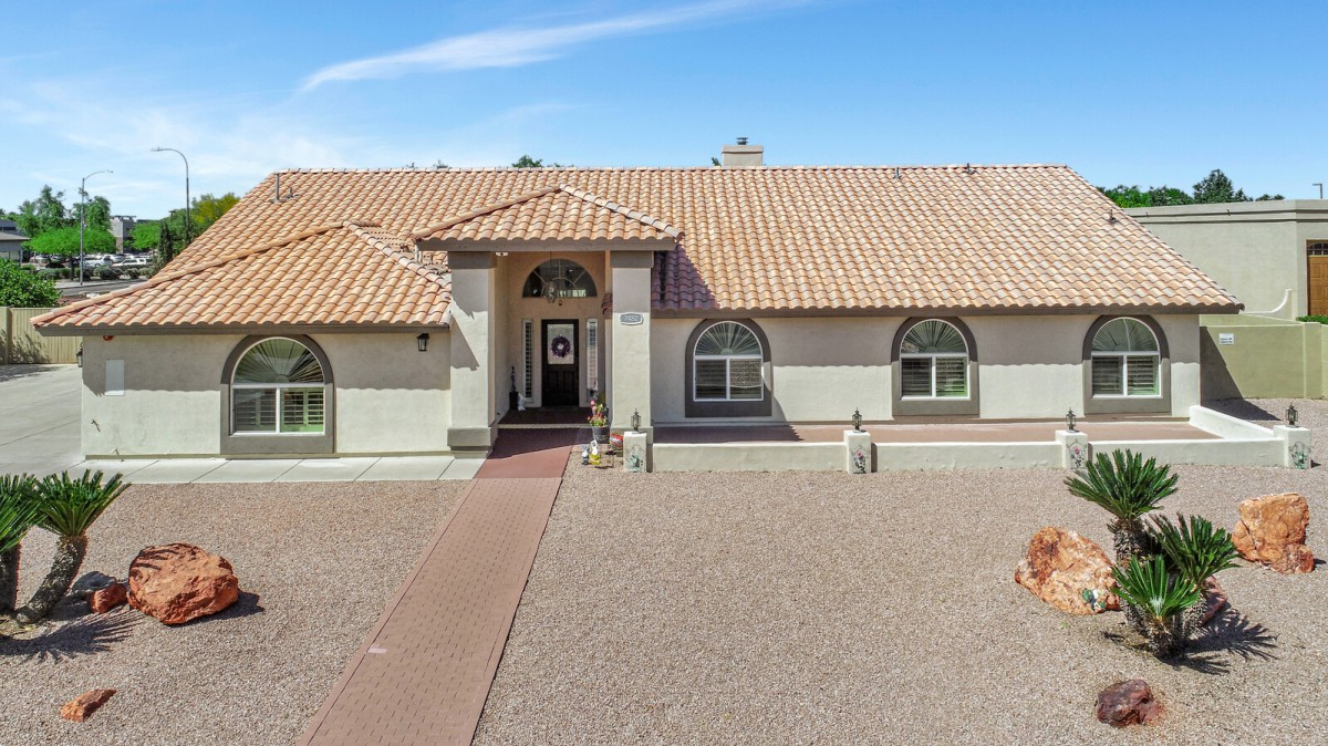 A single-story house with a tiled roof and arched windows, featuring a spacious driveway.