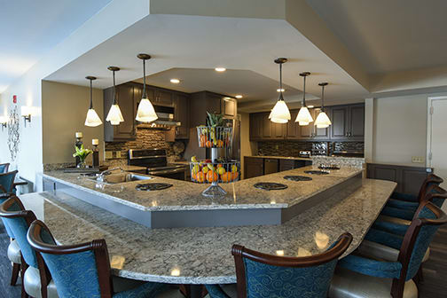 A modern kitchen with granite countertops, pendant lights, and bar seating.
