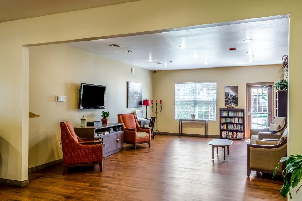 A cozy living room with comfortable chairs, a television, and a wooden floor.