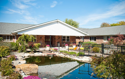A beautiful house with a tranquil garden and pond under a clear blue sky.
