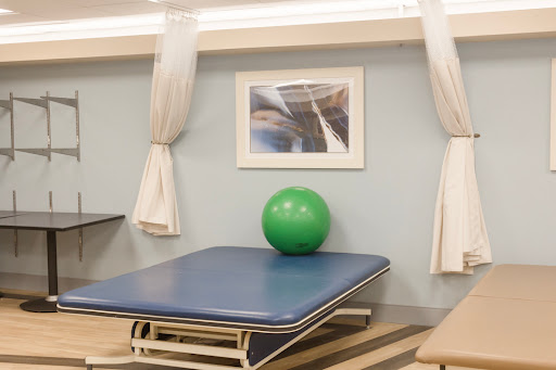 A serene therapy room featuring a blue exercise table and a vibrant green exercise ball.